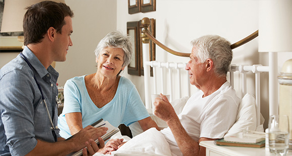 caregiver discussing health with elderly couple in bedroom promoting well being for seniors aged 6 and up