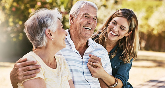 happy elderly couple laughing with a young woman outside enjoying a joyful moment together celebrating ten years of memories